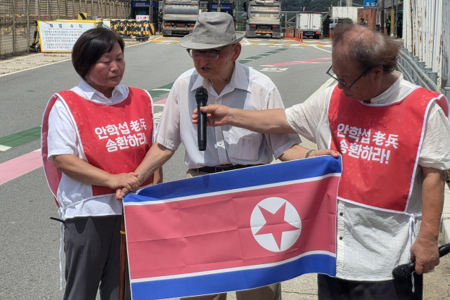 20일 오전 경기도 파주시 통일대교 남단에서 북한 송환을 요구한 비전향장기수 안학섭 씨(가운데)가 인공기를 펼쳐 들고 있다. 연합뉴스