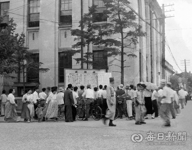 1955년 9월 16일 한국은행 대구지점 속보판 앞에서 시민들이 대구매일신문(현 매일신문) 사설이 이적 행위를 했다고 게시한 테러범의 공갈문을 보고 있다. 사진=매일아카이빙센터
