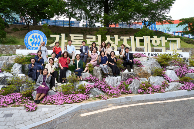 가톨릭상지대 입간판 앞에서 학교 관계자들이 기념촬영을 하고 있다. 가톨릭상지대 제공