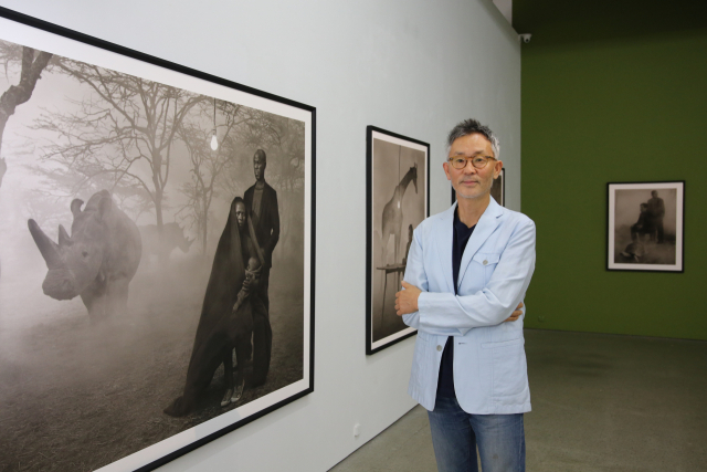 지난달 29일 아트스페이스 루모스에서 만난 석재현 사진가가 자신이 기획한 닉 브랜트의 전시작을 배경으로 포즈를 취하고 있다. 김도훈 기자