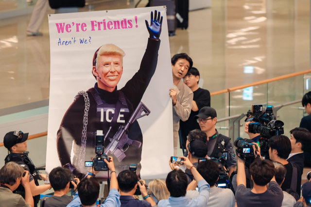 미국 이민당국에 의해 조지아주에 구금됐던 한국인 근로자들이 귀국한 12일 인천국제공항 제2여객터미널 입국장에서 이제석 이제석광고연구소 대표가 트럼프 미국 대통령의 모습이 담긴 플래카드 퍼포먼스를 벌이고 있다. 연합뉴스