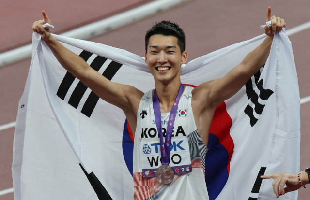 2025 세계육상선수권 남자 높이뛰기에서 은메달을 따낸 우상혁이 태극기를 두르며 기뻐하고 있다. 연합뉴스