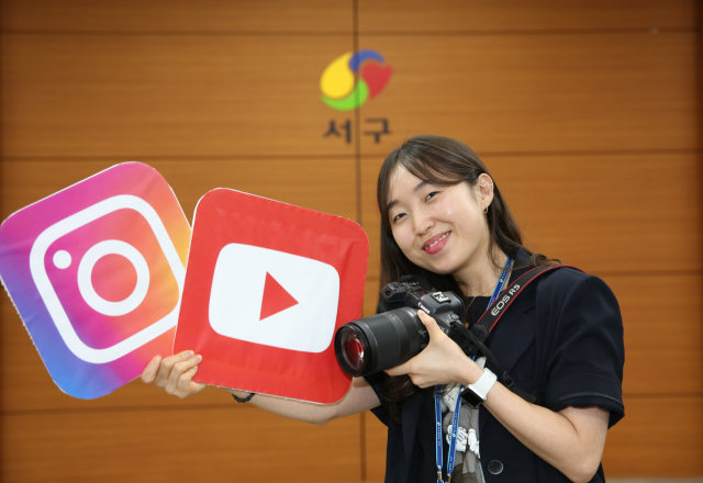 김표경 주무관이 대구 서구청 대회의실에서 유튜브와 인스타그램 로고가 그려진 팻말을 들고 포즈를 취하고 있다. 김도훈 기자