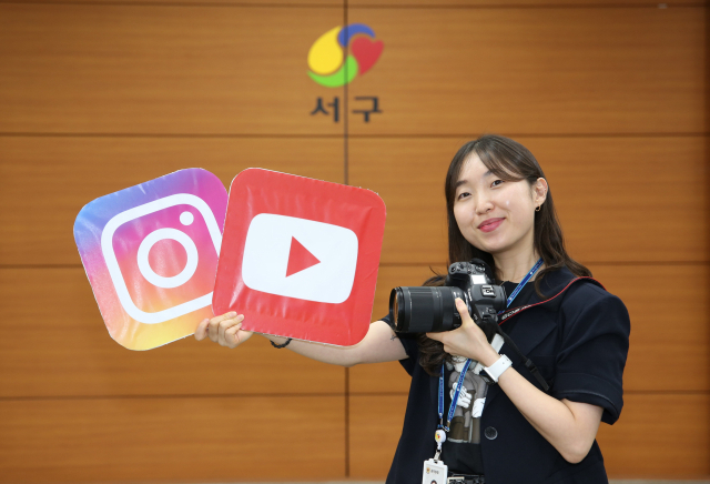 김표경 주무관이 대구 서구청 대회의실에서 유튜브와 인스타그램 로고가 그려진 팻말을 들고 포즈를 취하고 있다. 김도훈 기자