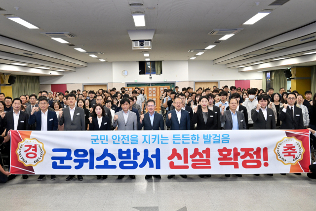 김진열 군수를 비롯한 대구 군위군 공무원들이 군위소방서 신설을 환영하는 현수막 앞에서 파이팅을 외치고 있다. 군위군 제공