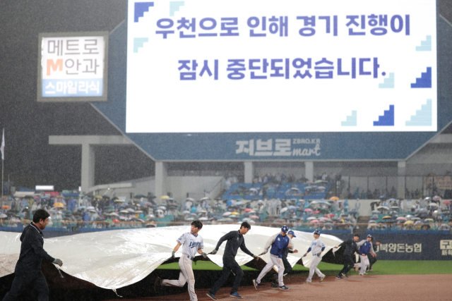 13일 삼성 라이온즈와 SSG 랜더스의 프로야구 준플레이오프 3차전이 열린 대구 삼성라이온즈파크. 1회말 경기 도중 갑작스런 폭우로 경기가 중단되자 경기 진행 요원들이 급히 대형 방수포로 내야를 덮고 있다. 삼성 제공