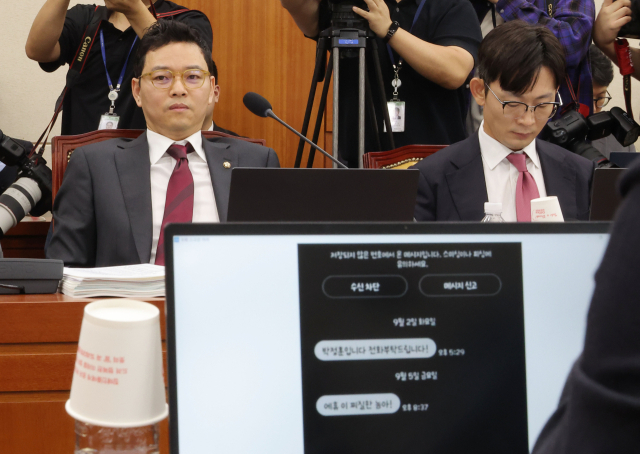 국민의힘 박정훈 의원이 16일 국회 과학기술정보방송통신위원회에서 열린 2025년도 국정감사에서 더불어민주당 김우영 의원이 공개한 자신의 휴대전화 문자를 바라보고 있다. 연합뉴스