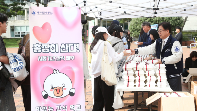 성한기 대구가톨릭대 총장이 중간고사 기간을 맞아 중앙도서관 앞에서 학생들에게 간식을 나눠주며 응원의 인사를 전하고 있다. 대구가톨릭대 제공