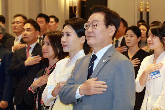 이재명 대통령과 김혜경 여사가 26일 말레이시아 쿠알라룸푸르 한 호텔에서 열린 동포 만찬 간담회에서 국기에 경례하고 있다. 연합뉴스
