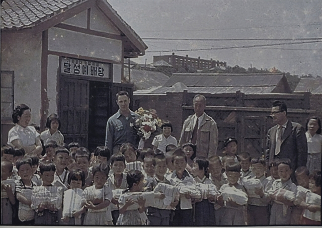 메노나이트 선교사가 대구 복현동 고아원 어린이들에게 선물을 전달하고 기념촬영을 하고 있다. MCC 제공