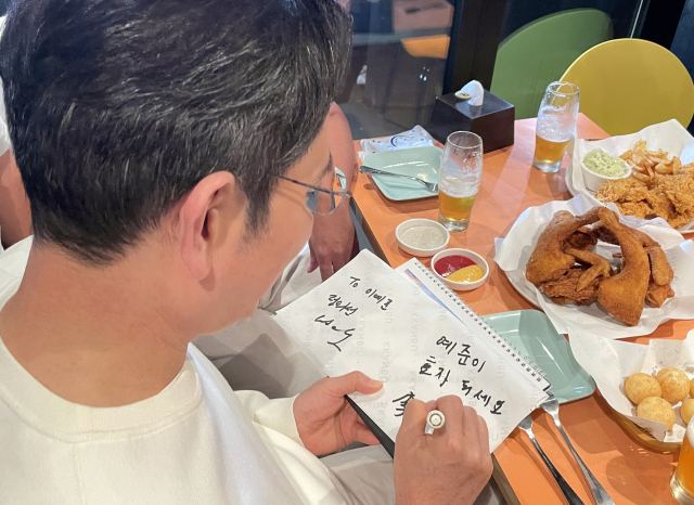 이재용 삼성전자 회장이 30일 서울 삼성동 한 치킨집에서 진행된 젠슨 황 엔비디아 최고경영자, 정의선 현대차그룹 회장과의 치맥 회동에서 한 어린이에게 사인을 해주고 있다. 연합뉴스