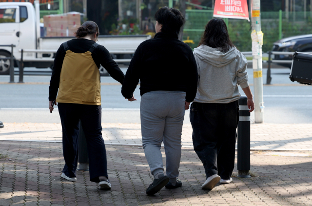 5일 오전 대구 북구에서 발달장애인 나현(23·가명) 씨가 치료사들과 손을 잡고 센터로 이동하고 있다. 김영진 기자 kyjmaeil@imaeil.com