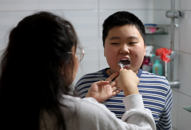 5일 대구 북구의 한 아파트에서 발달장애아 민재가 어머니의 도움을 받으며 양치질을 하고 있다. 김영진 기자 kyjmaeil@imaeil.com
