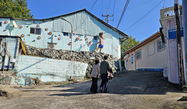 언덕 벽에는 아이가 바다를 향해 달려가는 장식이 설치되어 있다. 언덕을 오르는 두 사람의 발걸음이 마치 아이의 친구 같다.