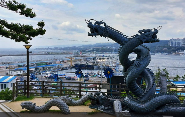 구룡포 공원의 아홉마리 용이 승천하는 모습의 조형물.조형물 뒷편으로 구룡포 항구가 보인다.