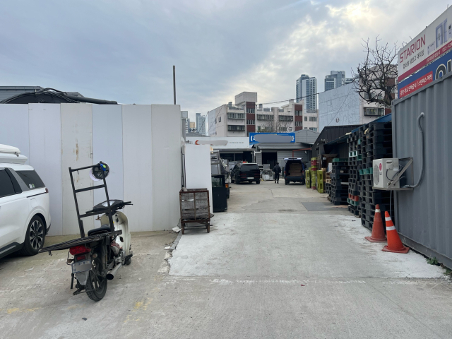 흰색 가벽이 설치된 주차타워 건설 현장과 주방용품 판매 매장 사이가 벌어져 있는 모습. 정두나 기자.