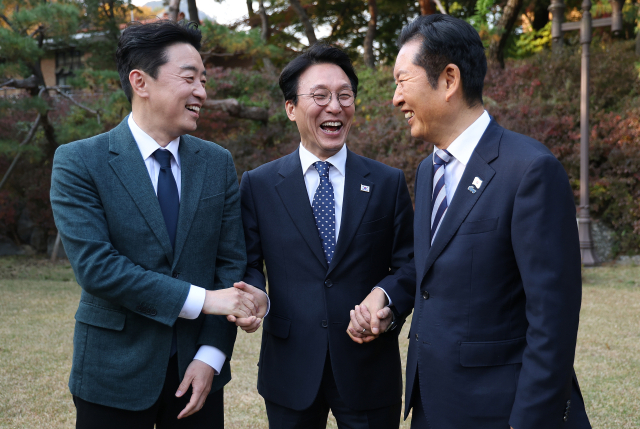 김민석 국무총리(가운데)가 9일 서울 종로구 총리공관에서 열린 고위당정협의회에서 강훈식 대통령 비서실장(왼쪽), 더불어민주당 정청래 대표와 손을 잡고 있다. 연합뉴스