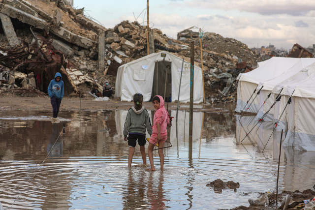 25일(현지시간) 가자지구 동쪽에 있는 알 자이툰 지역에서 비가 오는 날 텐트 근처 웅덩이를 걷고 있는 팔레스타인 소녀들. EPA 연합뉴스