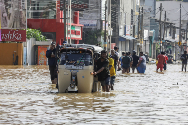 11월 30일(현지시간) 스리랑카 콜롬보 교외에서 폭우로 도로가 침수되자 사람들이 물에 잠긴 길을 지나가고 있는 모습. EPA 연합뉴스