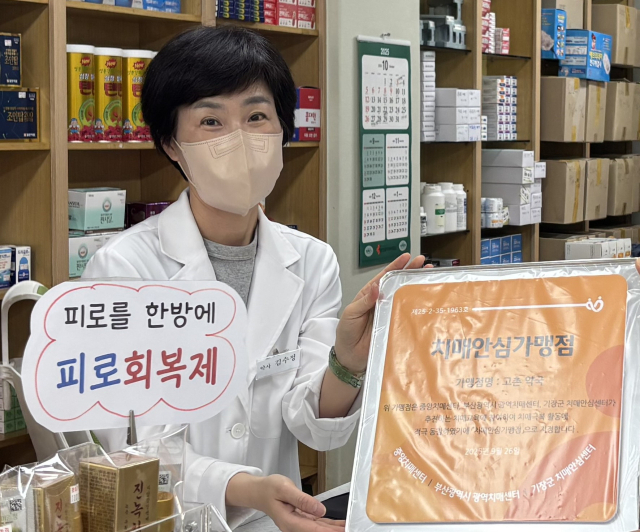 부산 기장군 철마면 고촌약국 김수정 대표가 기장군 치매안심가맹점 지정 현판을 전달받고 있다. [사진=기장군]