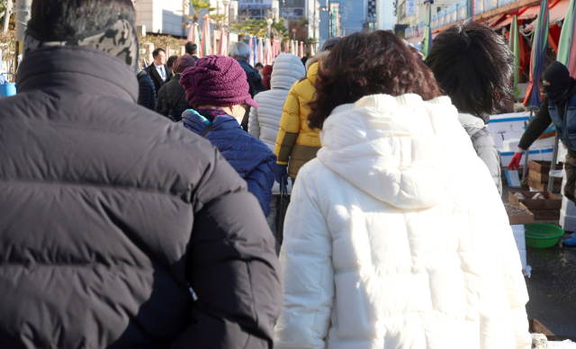 최저 기온이 영하를 기록한 3일 오전 경남 창원시 마산합포구 마산어시장에서 두꺼운 패딩 점퍼 등을 착용한 시민이 찬 바람을 막으며 이동하고 있다. 연합뉴스