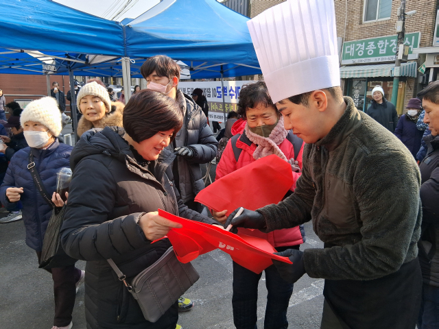 지난 4일 가수 박군이 대구 서구 신평리시장에서 떡국 나눔 봉사를 진행하며 시민에게 싸인해주는 모습. 대구 서구 신평리시장 상인회 제공