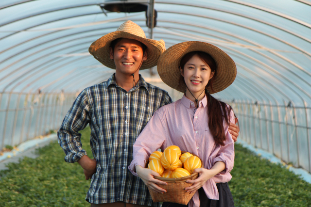 조상범·이지은 부부가 농장에서 수확한 참외를 들고 서 있다. 둘은 2017년 결혼해 함께 귀향했다. 조상범 씨 제공