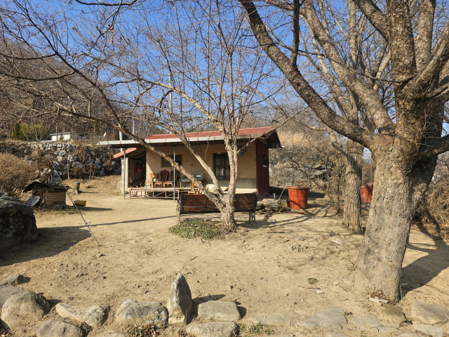 붉은 함석지붕을 머리에 인 흙집이 빌뱅이 언덕의 품에 안기듯 평온하게 자리하고 있다.