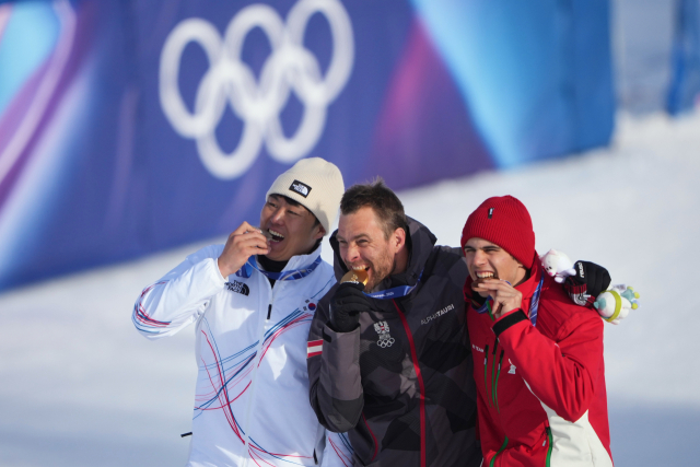 김상겸이 8일(현지 시간) 이탈리아 리비뇨 스노 파크에서 열린 2026 밀라노 동계 올림픽 스노보드 남자 평행대회전 준결승에 출전, 은메달을 목에 건 뒤 시상대에 올라 벤야민 카를(가운데·금메달), 테르벨 잠피로프(동메달)와 함께 메달을 깨무는 세리머니를 선보이고 있다. AP 연합뉴스