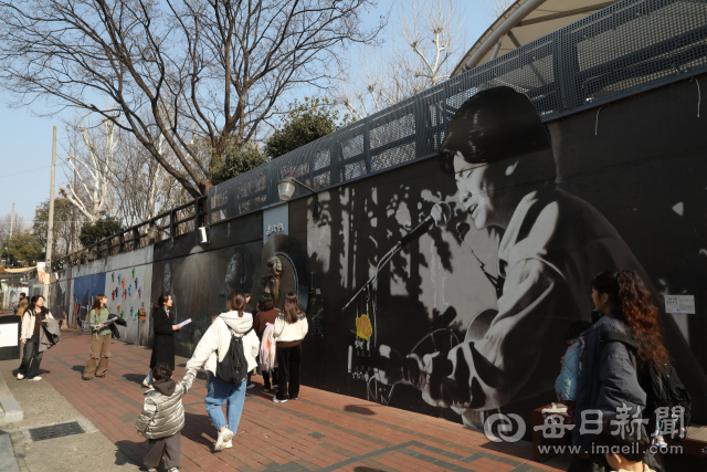 신천대로의 소음을 벗어나 골목으로 들어선 방문객들이 김광석 벽화 앞에 발걸음을 멈추고 있다. 노랫말이 적힌 벽과 기타 선율이 흐르는 골목은 도심 속 또 다른 풍경을 만들어낸다. 정운철 기자 woon@imaeil.com