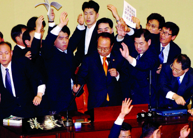 2004년 3월12일 박관용 국회의장이 국회 본회의에서 경위들의 호위속에 노무현 대통령 탄핵안을 가결한 후 산회를 선포하고 있다.