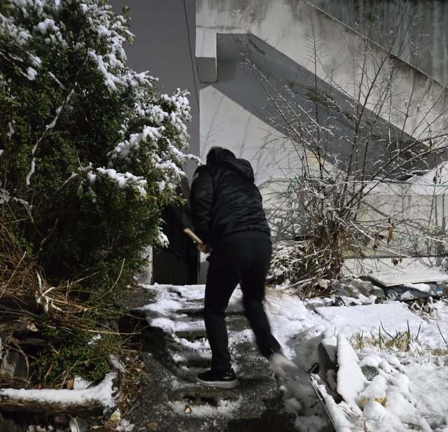 24일 저녁 대설주의보가 발효된 대구 북구의 한 골목길에서 김지만 국민의힘 대구 북구청장 출마예정자가 평상복 차림으로 눈 쌓인 계단을 쓸고 있다. 독자 제공.
