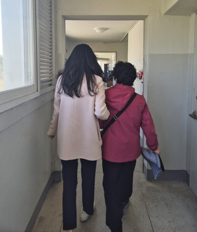 정연휘 사회복지사(왼쪽)가 어르신의 팔을 붙잡고 복도를 함께 걷고 있다. 재가복지 현장은 이렇게 어르신의 일상 곁에서 시작된다.