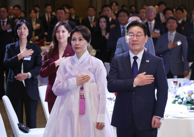 이재명 대통령과 김혜경 여사가 1일 싱가포르 한 호텔에서 열린 동포 만찬간담회에서 국기에 경례하고 있다. 연합뉴스