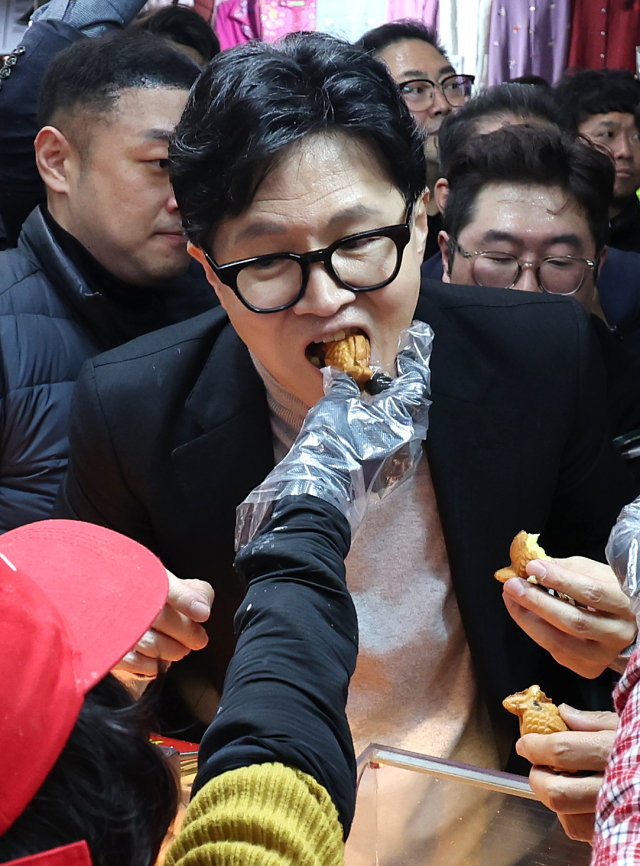 한동훈 국민의힘 전 대표가 27일 오후 대구 서문시장에 도착해 상인들이 건네는 음식을 먹고 있다. 연합뉴스