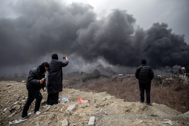 8일 이란 테헤란 북서쪽 석유 저장시설이 불타는 모습을 시민들이 지켜보고 있다. UPI 연합뉴스