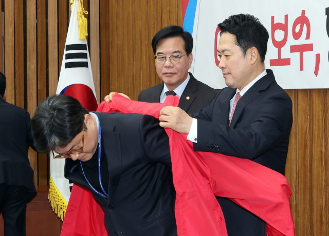 국민의힘 장동혁 대표가 11일 국회에서 열린 지역발전 인재 영입 환영식에서 영입 인재에게 당 점퍼를 입혀주고 있다. 왼쪽은 송언석 원내대표. 연합뉴스