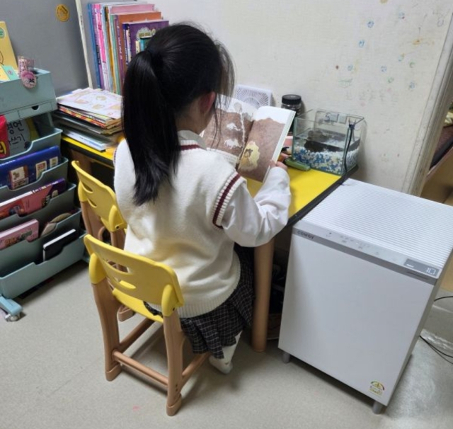 부산항만공사가 지원한 공기청정기가 설치된 가운데 한 아동이 실내에서 책을 읽고 있다. [사진=부산항만공사]