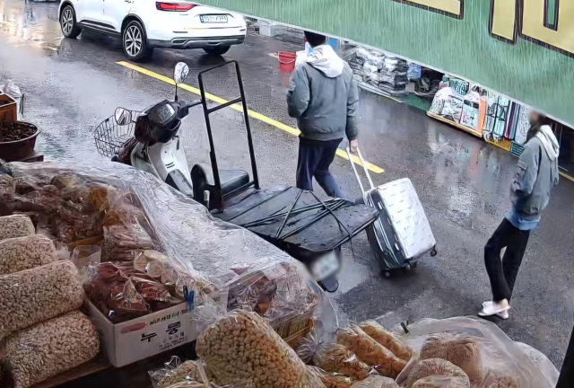 대구 북부경찰서는 1일 50대 여성의 시신을 캐리어에 담아 북구 칠성동 신천에 유기한 혐의로 20대 딸과 사위를 붙잡아 수사 중이다. 사진은 지난 18일 이들 부부가 캐리어를 끌고 중구 주거지에서 신천으로 이동하는 모습이 담긴 폐쇄회로TV 영상 중 일부. 연합뉴스