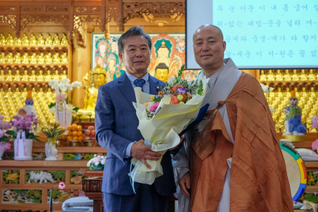 선광사 제7대 신도회장 추대 법회에서 이용희 신임 신도회장(죄측)이 주지스님으로부터 축하 꽃다발을 받고 있다. 선광사측 제공