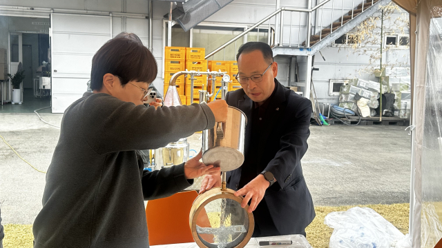 인삼막걸리를 증류해 만든 남산인 소주를 강매영과장(왼쪽)과 정희수 농업기술센터 소장(오른쪽)이 미니오크통에 넣고 있다. 영주시 제공