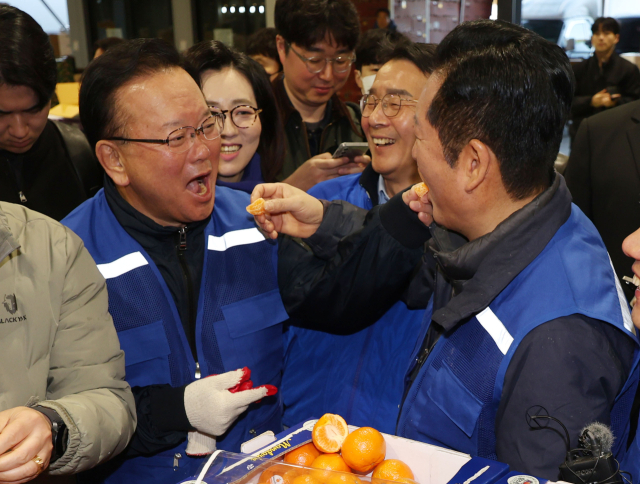 더불어민주당 정청래 대표와 민주당의 대구시장 후보로 확정된 김부겸 전 총리가 8일 오전 대구 북구 매천동 농수산물도매시장을 찾아 민생현장을 살피며 귤을 맛보고 있다. 연합뉴스