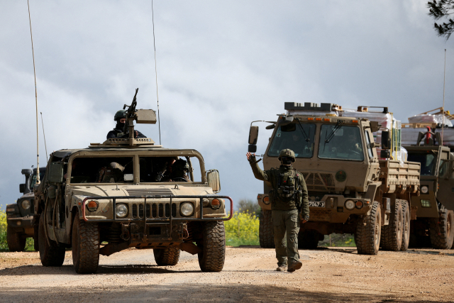 FILE PHOTO: An Israeli soldier gestures while walking next to military vehicles, after Israel forces launched a new campaign against Iran-backed Hezbollah in southern Lebanon, near the Israel-Lebanon border in northern Israel, March 30, 2026. REUTERS/Shir Torem/File Photo