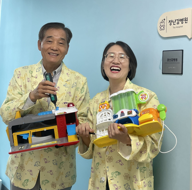 권혁환 씨(67·왼쪽)와 정현희 씨(47)가 수리한 장난감을 들고 미소 짓고 있다. 이들은 자원봉사로 장난감을 고치며 아이들의 추억을 이어가고 있다.