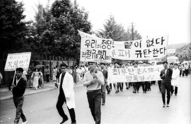 1964년 6월 3일 11시 서울대 약대생들이 플레카드를 들교 교문 밖으로 나서고 있다. 이날 서울 국회의사당 앞에는 12개 대학생, 시민 등 2만여명이 모였으며 청와대로 진출하다 경찰의 최루탄 발포에 맞서 투석전을 벌였다. 매일DB