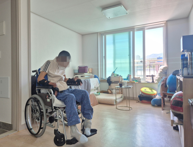 김명석(가명.44) 씨가 사지 강직 증세로 몸을 축 늘어뜨린 채 휠체어에 앉아 있다. 사진 속 휠체어는 지난달 돌아가신 어머니 앞으로 나온 기구로 최근 관계기관에서 회수해갔다. 김지수 기자