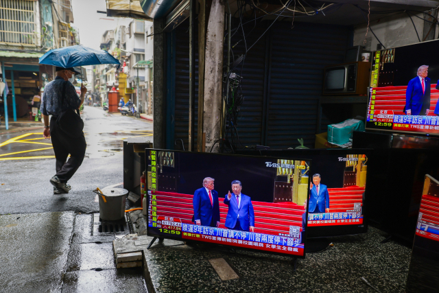 14일 대만 타이베이 시내에서 TV 화면이 진열된 중고 TV 수리점 앞을 한 보행자가 지나고 있다. 화면에는 미중정상회담 장면이 중계되고 있다. EPA 연합뉴스