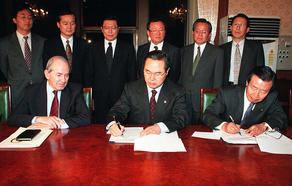 1997년 12월 3일 임창렬 경제부총리(중앙)와 이경식 한국은행총재(오른쪽)가 정부청사에서 캉드쉬 IMF(국제통화기금) 총재가 지켜보는 가운데 IMF 긴급자금 지원을 받기 위한 의향서에 서명하고 있다. 연합뉴스