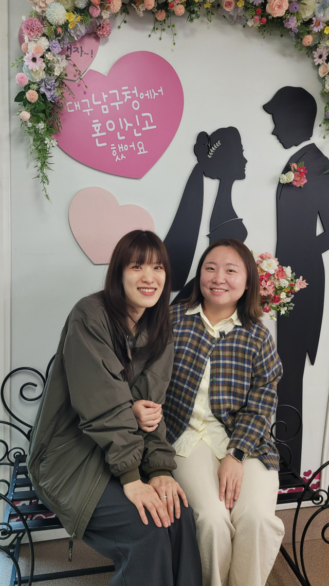 동성 연인인 최진아(왼쪽)·임아현 씨가 대구 남구청 혼인신고 포토존 앞에서 서로의 손을 맞잡고 있다. 