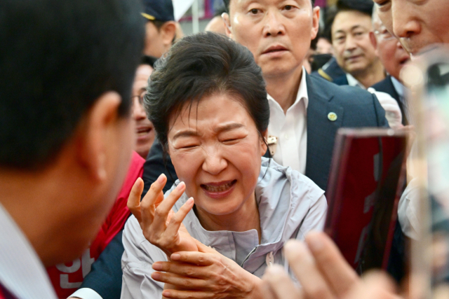 박근혜 전 대통령이 27일 경남 진주시 진주중앙시장에서 시민과 악수 후 손이 아픈 듯 인상을 쓰고 있다. 박 전 대통령은 이날 국민의힘 박완수 경남지사 후보, 같은 당 한경호 진주시장 후보 등을 지지하기 위해 진주를 방문했다. 연합뉴스